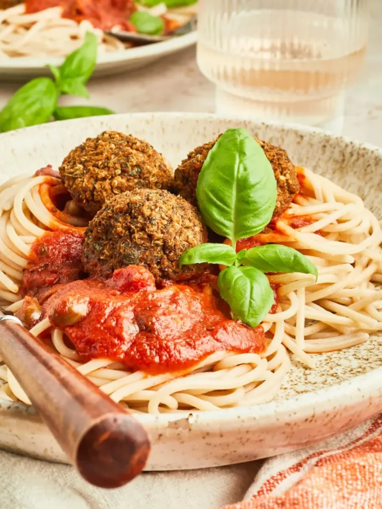 A plate of pasta with tomato sauce and quinoa meatballs on top.