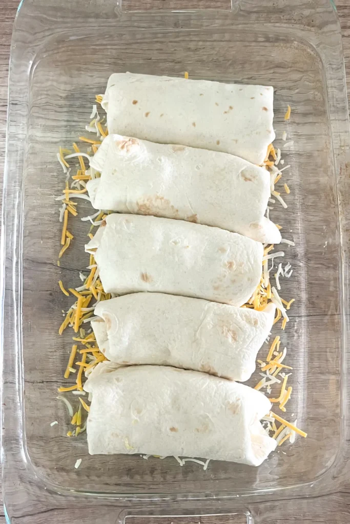 Rolled burritos in a bakng dish prior to baking.