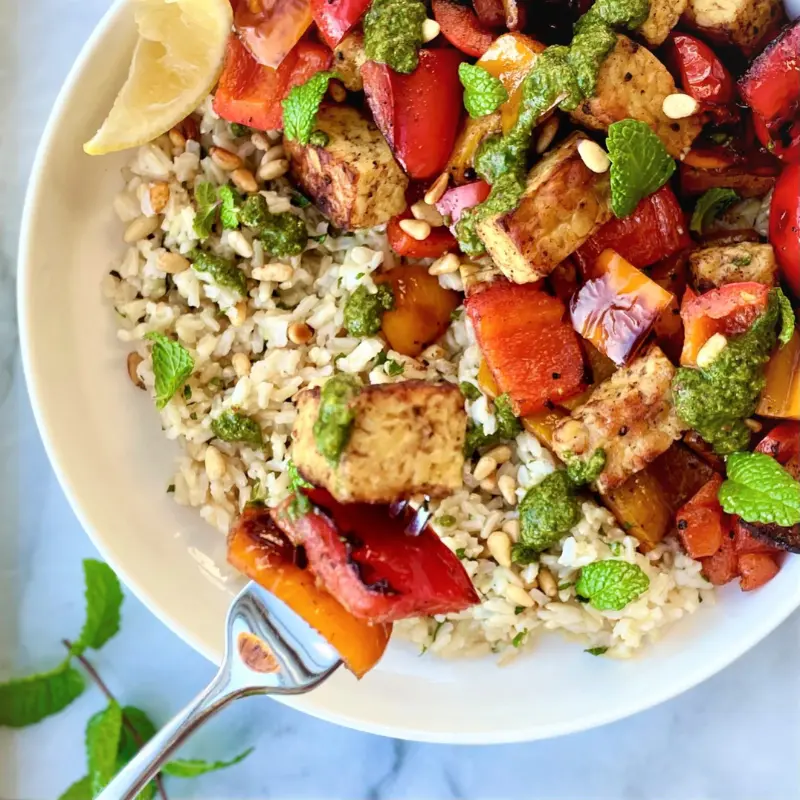 Tempeh and bell peppers served over rice in a bowl for a high protein plant-based meal.