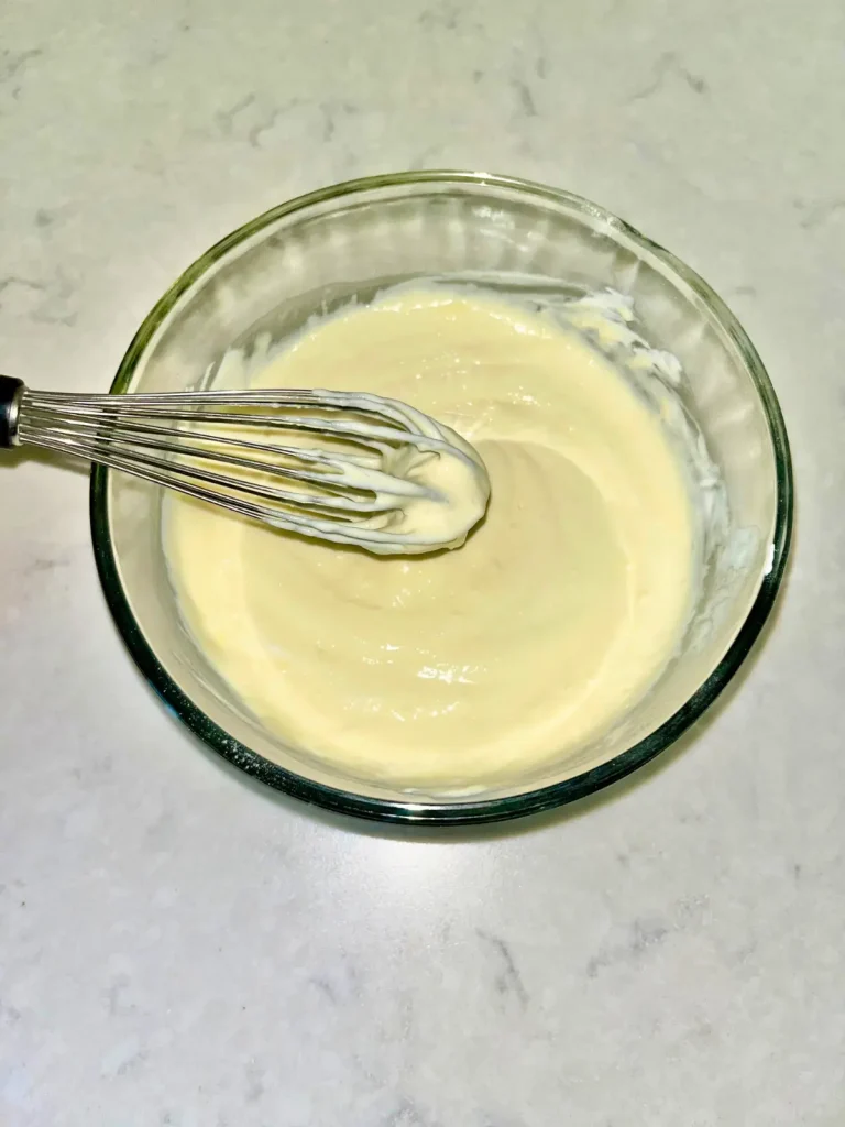 Whisking the pudding mixture in a glass bowl until smooth and well-combined.