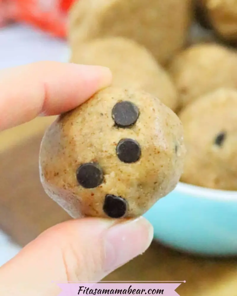 Someone holding a cookie dough protein bite in between their fingers.