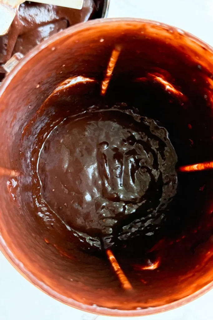 A birds-eye view looking into a blender cup with the dark chocolate sauce in it.