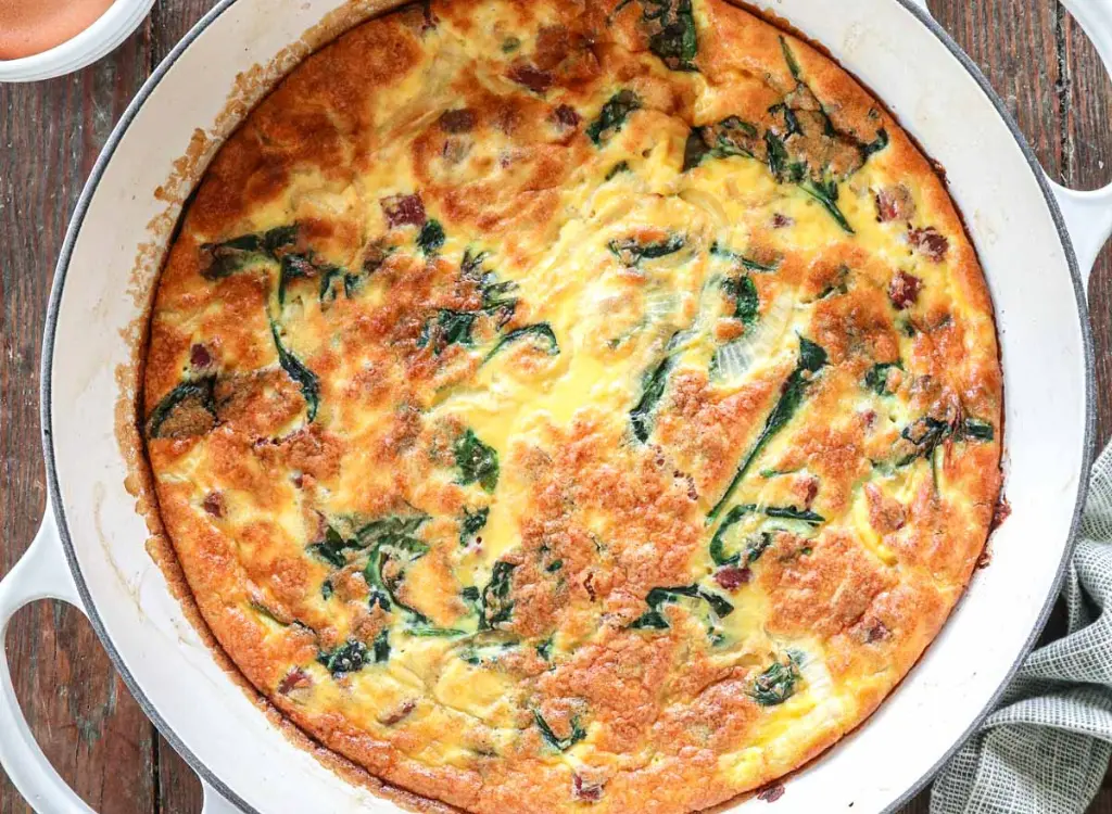 An easy, high protein breakfast casserole in a round ceramic baking dish on a counter.