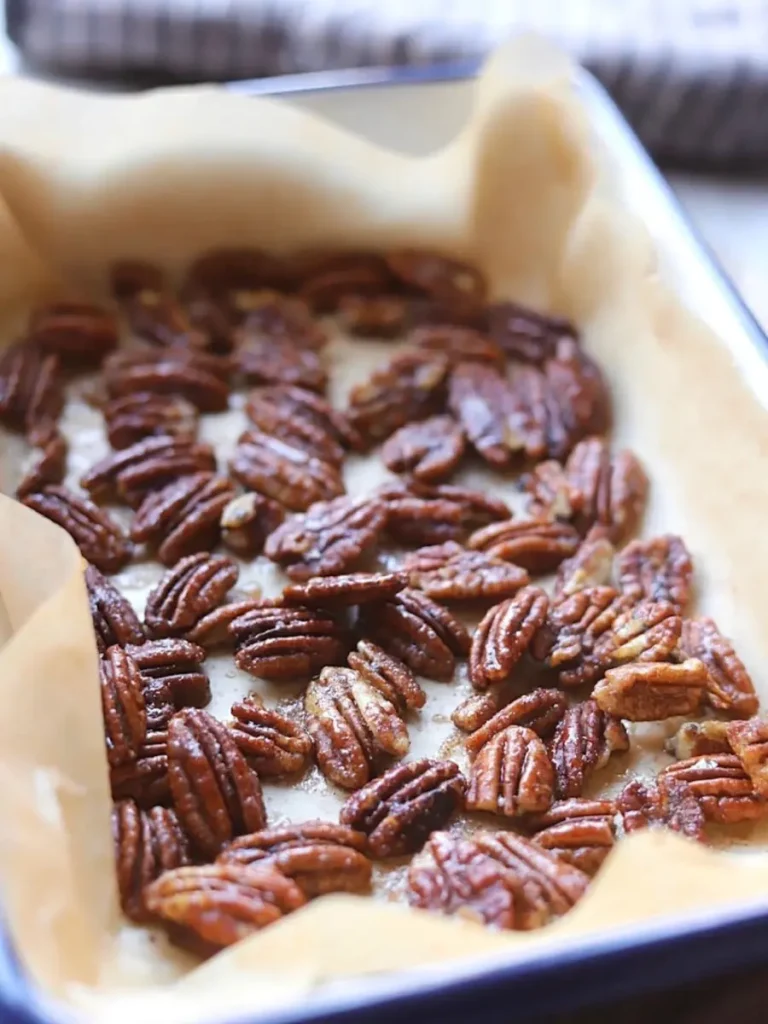 Honey glazed cinnamon pecans on a parchment paper lined baking sheet after cooking.