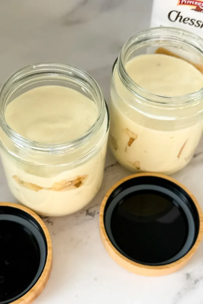 A view of two layered Chessmen banana pudding jars on a counter.