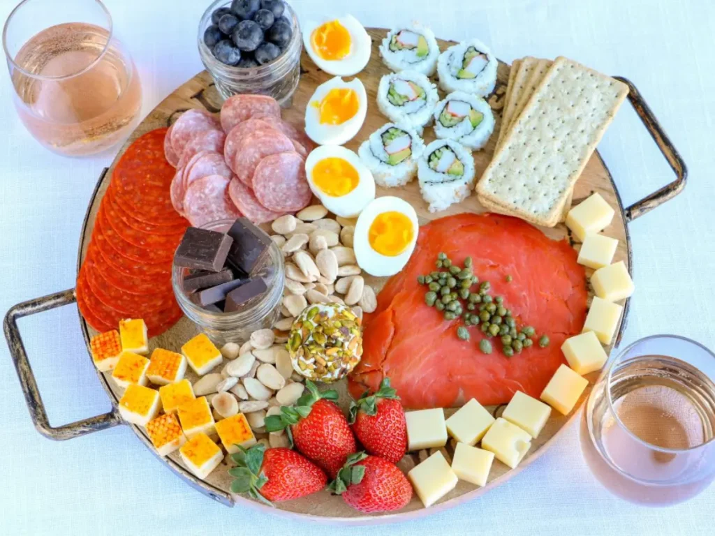 A charcutier board full of foods a pregnant woman can't have like sushi, raw fish, cheese and crackers.