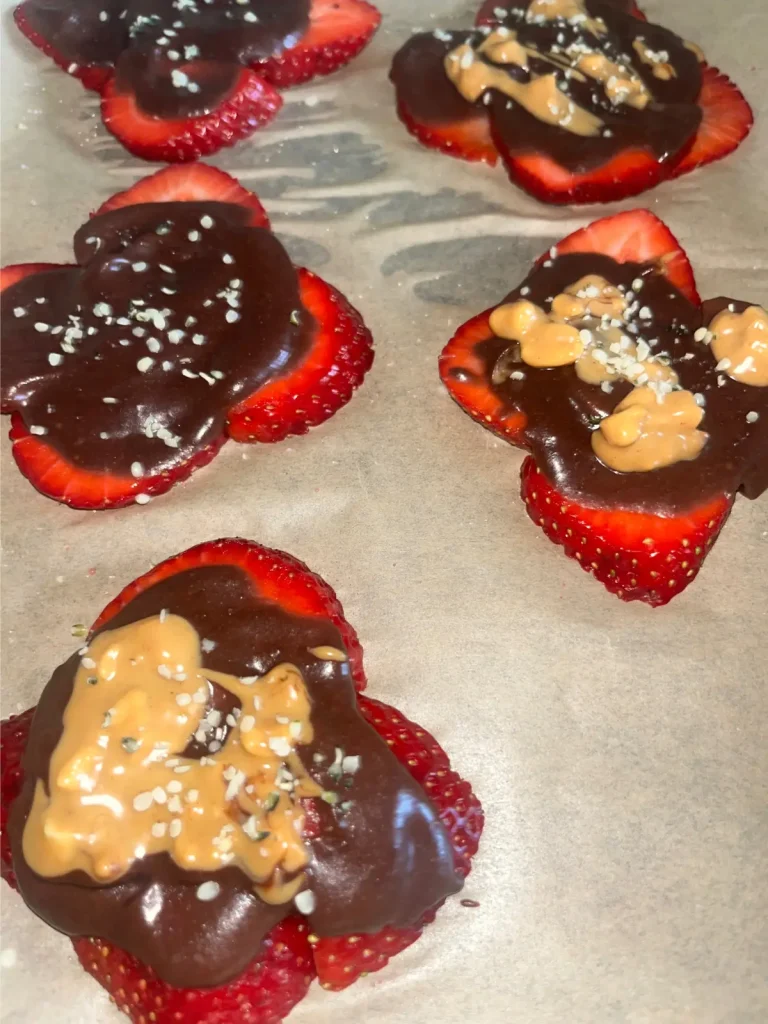 Strawberries arranged in a circle and covered with dark chocolate date sauce, peanut butter and sea salt.