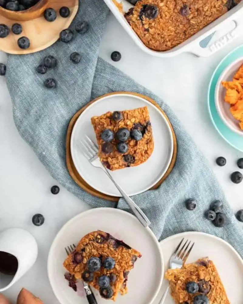 Plates with a piece of sweet potato oatmeal bake on them, topped with blueberries.