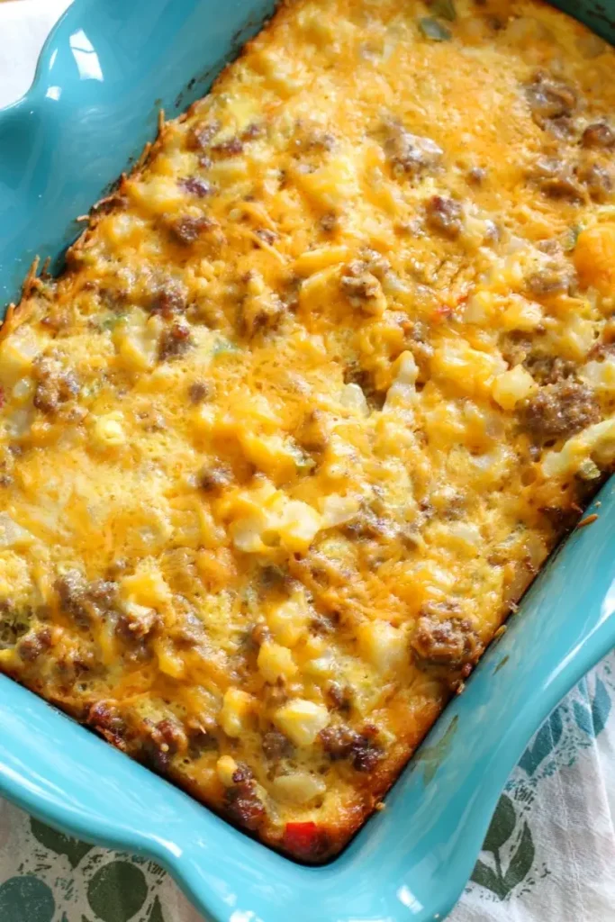 An egg and sausage breakfast casserole topped with cheese in a blue baking dish.