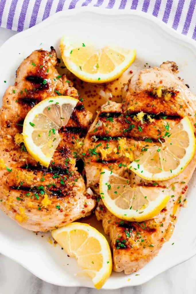 Grilled chicken breasts with slices of lemon on top.