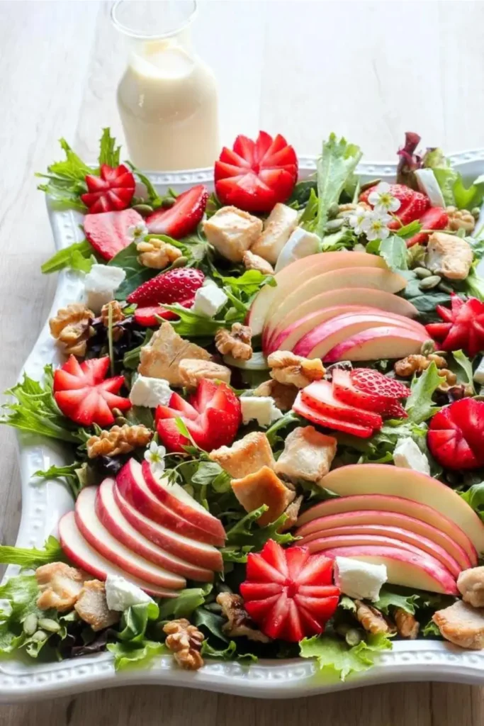 Apple, strawberry and chicken salad with a creamy maple dressing on a large platter.