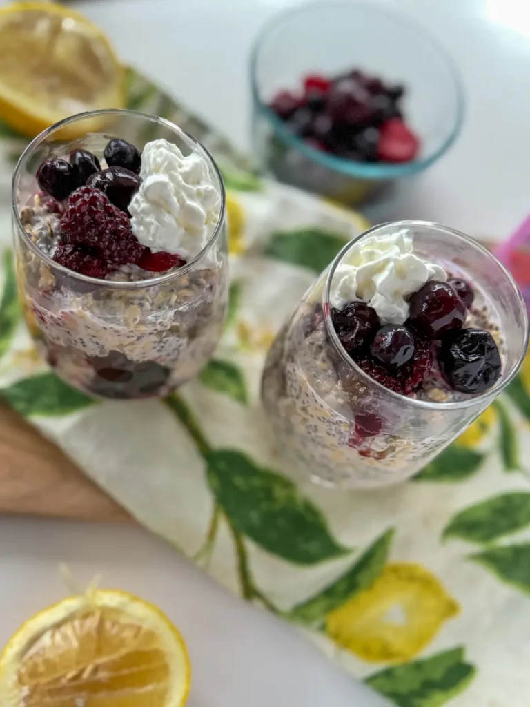 Two glasses of overnight oats with kefir on a hand towel on the counter.