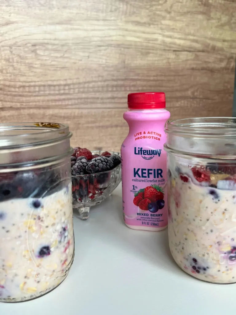 Two jars of overnight oats on a counter next to a bottle of kefir.