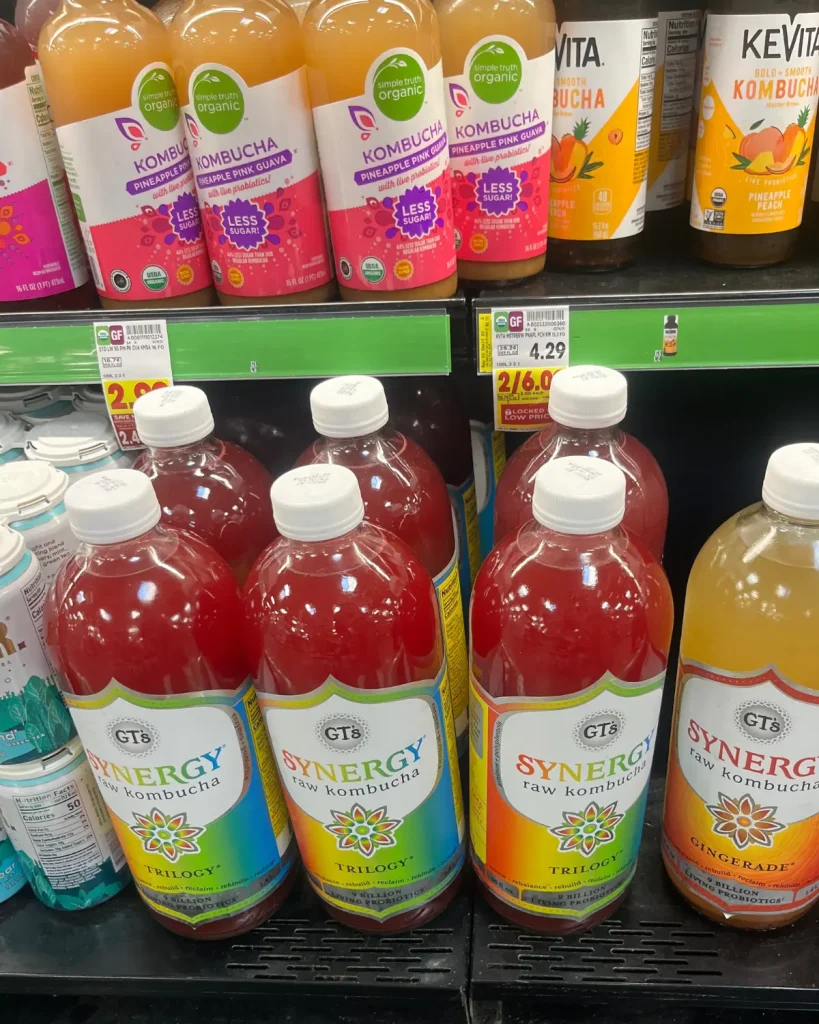 Various kombucha drinks on two shelves in the grocery store.