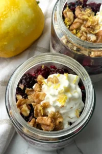 A birds-eye view of two glass jars of lemon berry kefir overnight oats on a yellow and white towel.