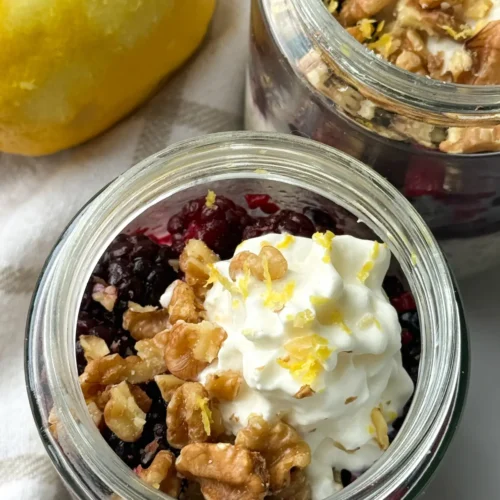 A birds-eye view of two glass jars of lemon berry kefir overnight oats on a yellow and white towel.