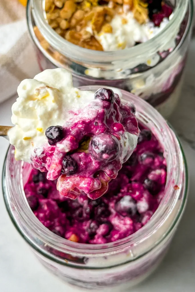 A close-up of a large scoop of overnight oats over a jar next to another glass of overnight oats.