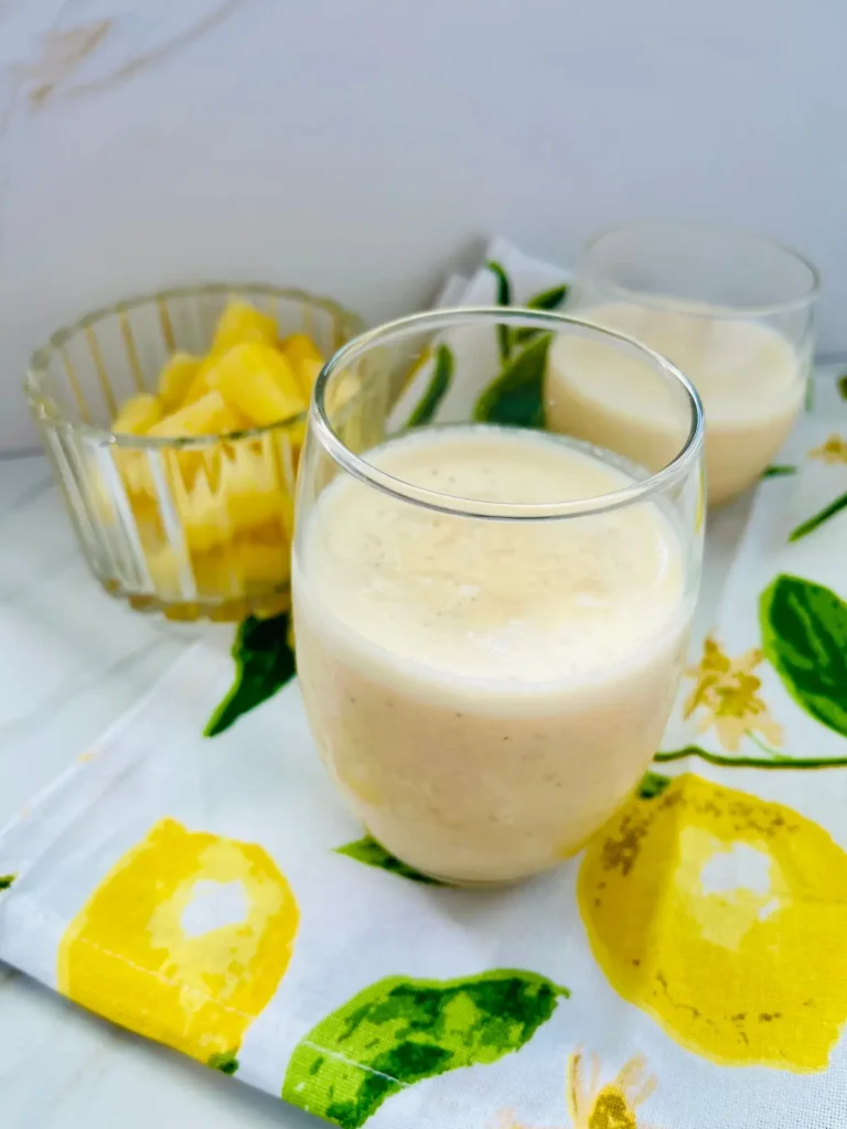 Two glasses of peach pineapple smoothies wiht kefir on a counter.