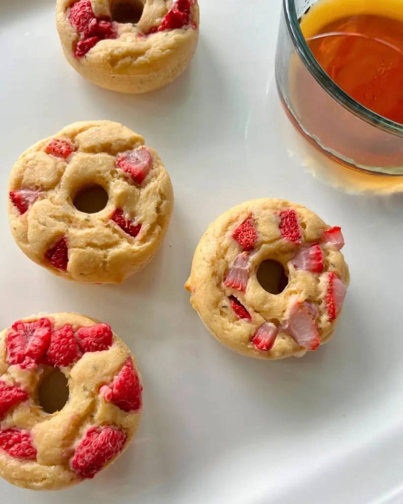 Protein donuts on a white platter next to a bowl of maple syrup.