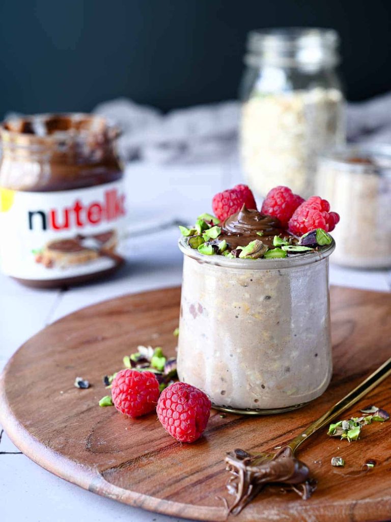 Overnight oats topped with raspberries and Nutella on a dining table.
