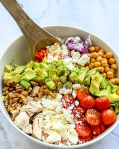 A large bowl of a lower carb Mediterranean chicken and tomato salad on a counter.