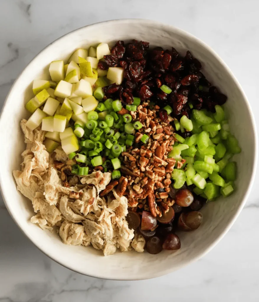 Cranberry chicken salad with celery, pecans and apples in a bowl.