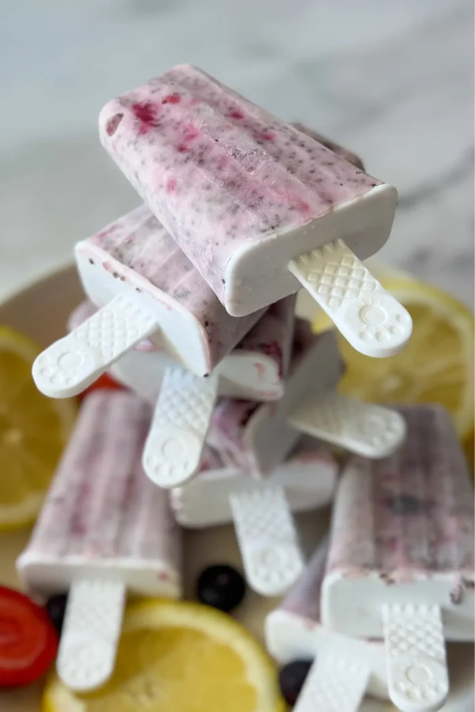 A stack of lemon and mixed berry popsicles stacked on top of one another on a plate.