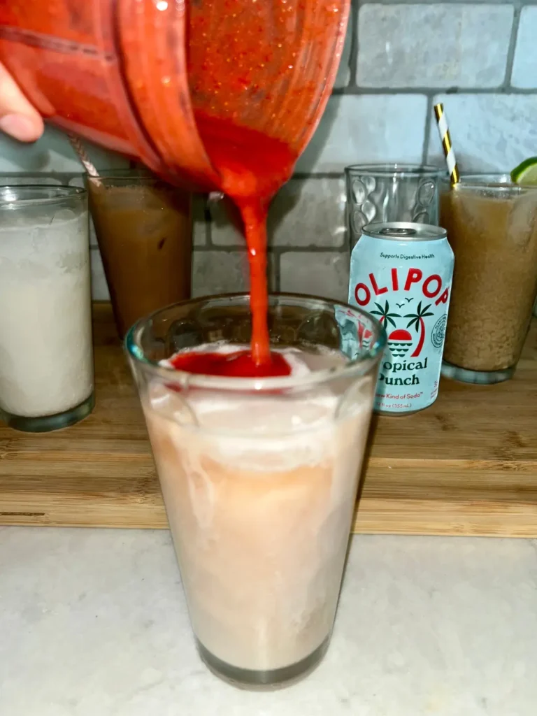Pouring the strawberry and lemon puree into the Olipop dirty soda.