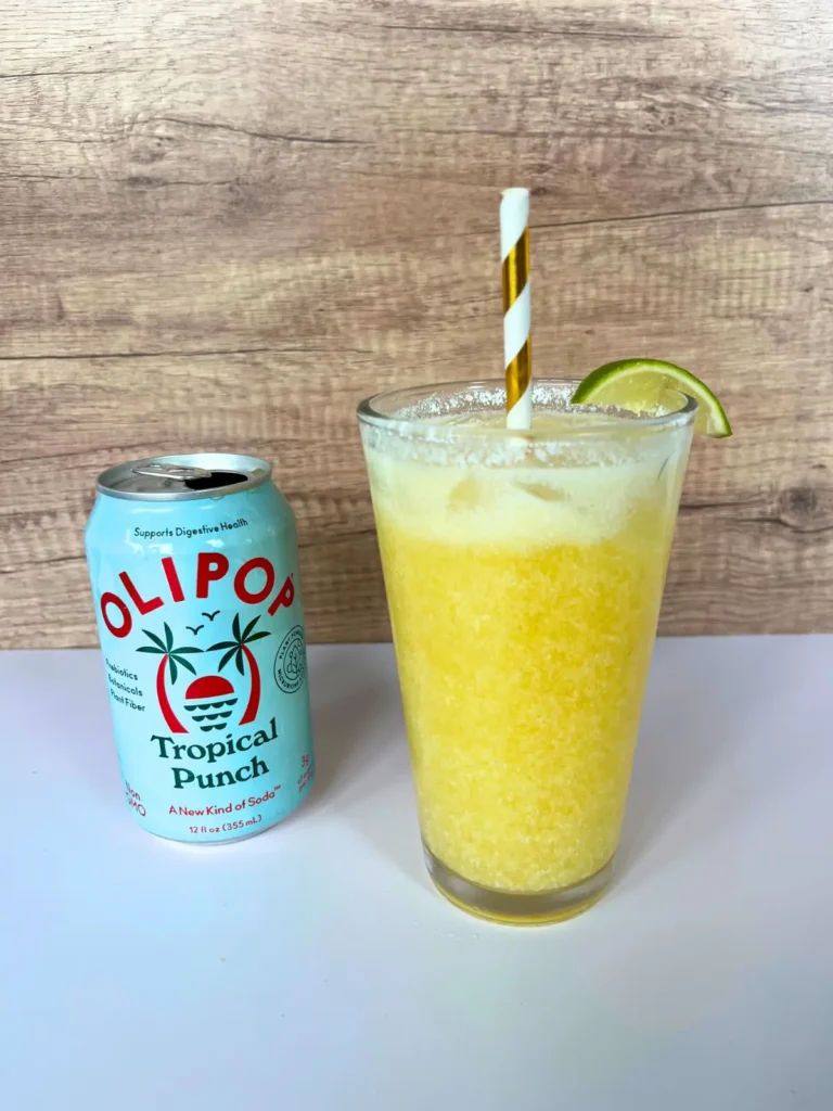 A pineapple cream dirty soda in a large glass next to a can of Tropical Punch Olipop.