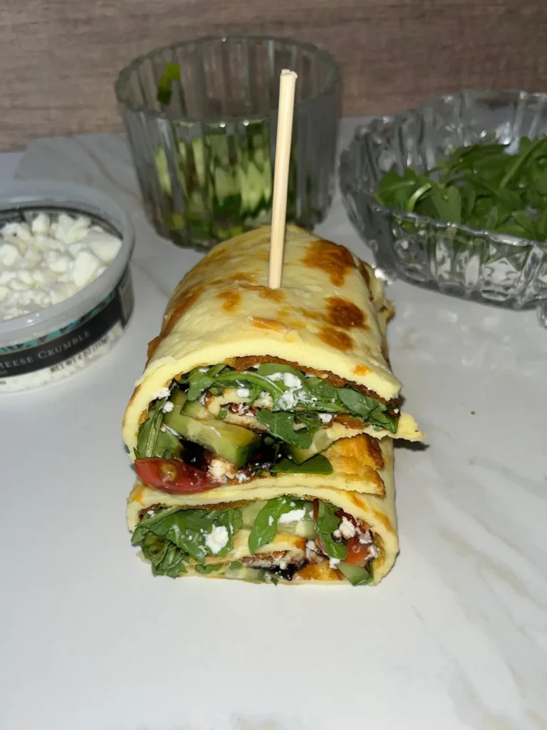 Two arugula salad cottage cheese flatbread halves stacked on top of one another on a white cutting board.