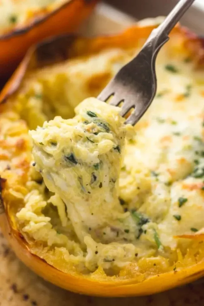 A close-up of a cheesy baked spaghetti squash with a fork pulling out a noodle on a baking sheet.