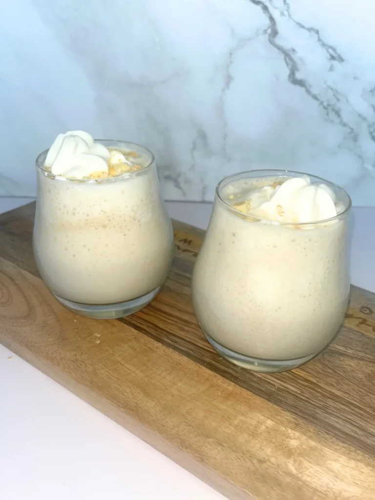 Banana pudding protein shakes in small glasses and topped with whipped cream.