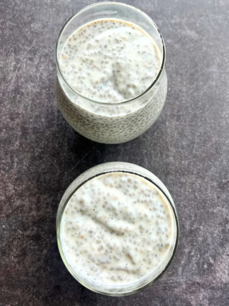 A birds-eye view of 2 glasses of chia pudding with kefir on a counter.