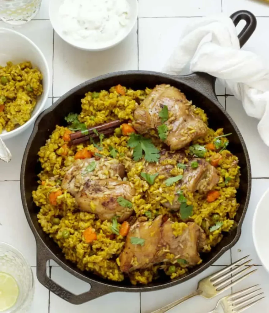 A large pan of chicken biryani with rice on a table.