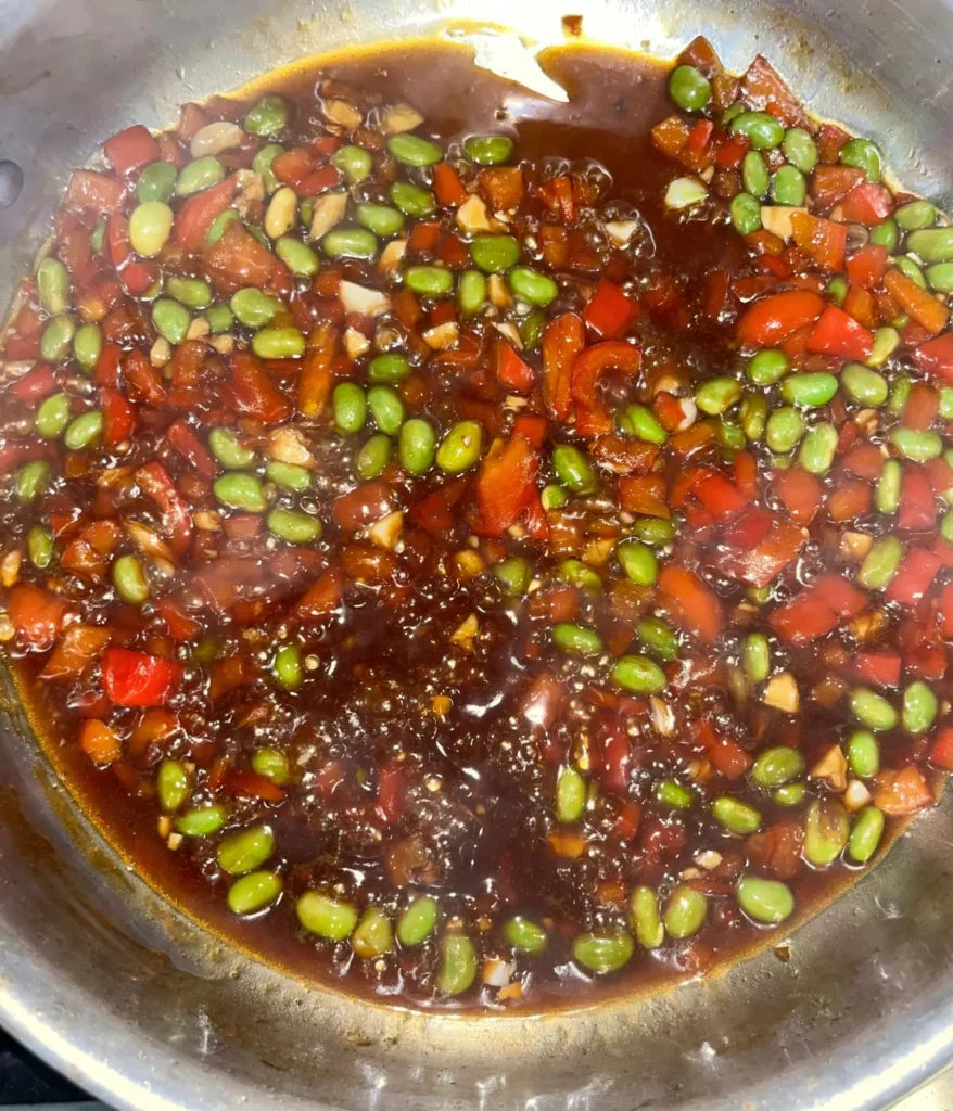 The stir fry sauce, edamame, and diced bell peppers simmering on the stove.