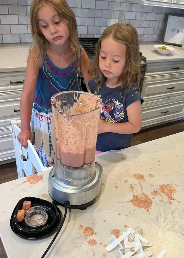 Two girls making a mess in the kitchen making popsicles.