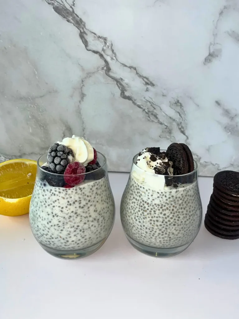 A lemon berry kefir chia pudding next to an Oreo kefir pudding on a counter next to a lemon and Oreo stacked on top of one another. 