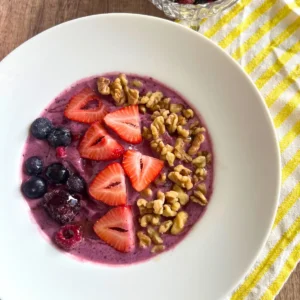 A lemon berry smoothie bowl with kefir on a yellow and white stripe towel.