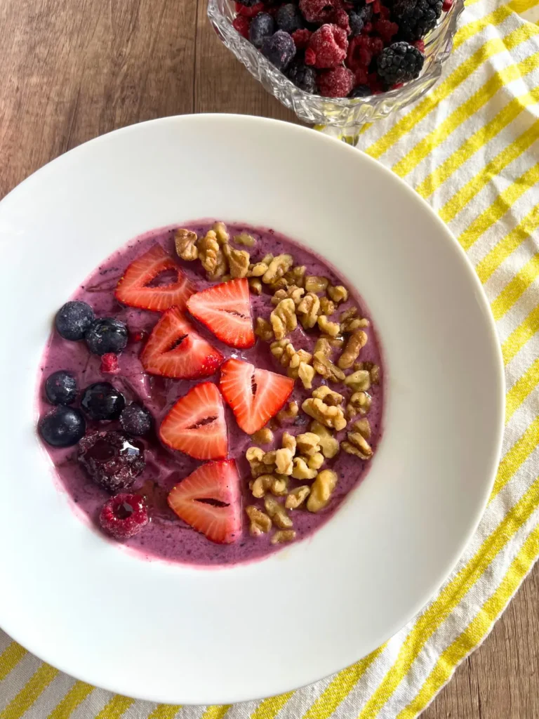 A lemon berry smoothie bowl with kefir on a yellow and white striped towel.