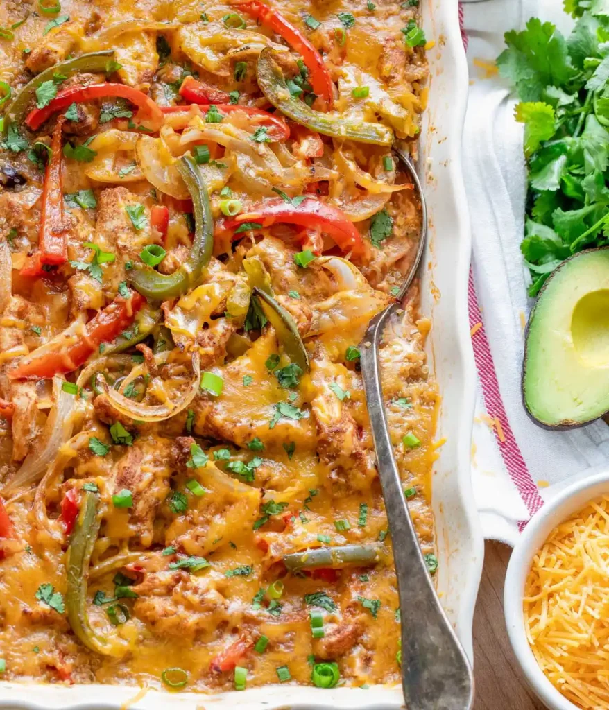 A Mexican fajita casserole right out of the oven on a table next to an avocado.