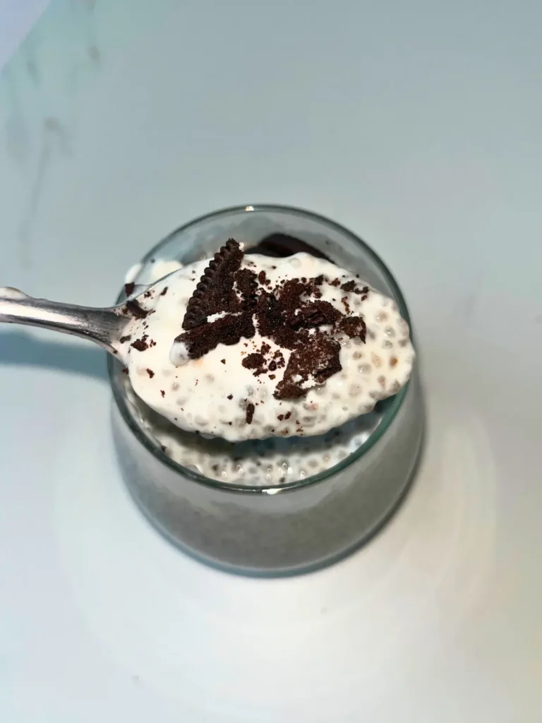 A large spoonful of kefir chia pudding topped with crushed Oreo crumbs with a glass jar of pudding in the background.