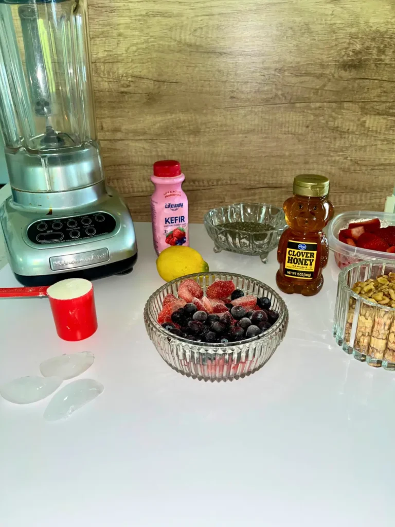 Smoothie bowl ingredients and a blender on a counter.