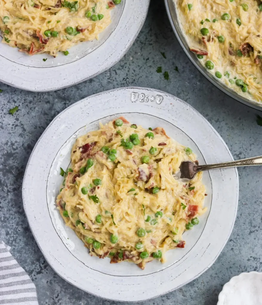 3 bowls of spaghetti squash carbonara with peas on a table.