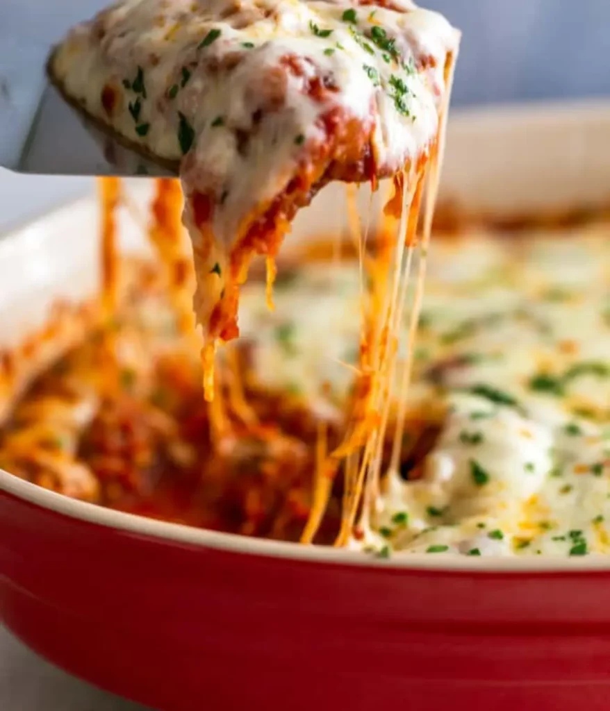 Cheesy spaghetti squash casserole being lifted up from the pan with a spatula.