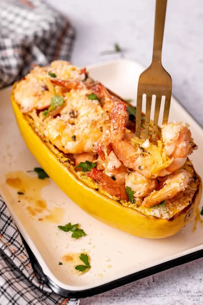 A spaghetti halve baked and filled with shrimp scampi on a white plate.