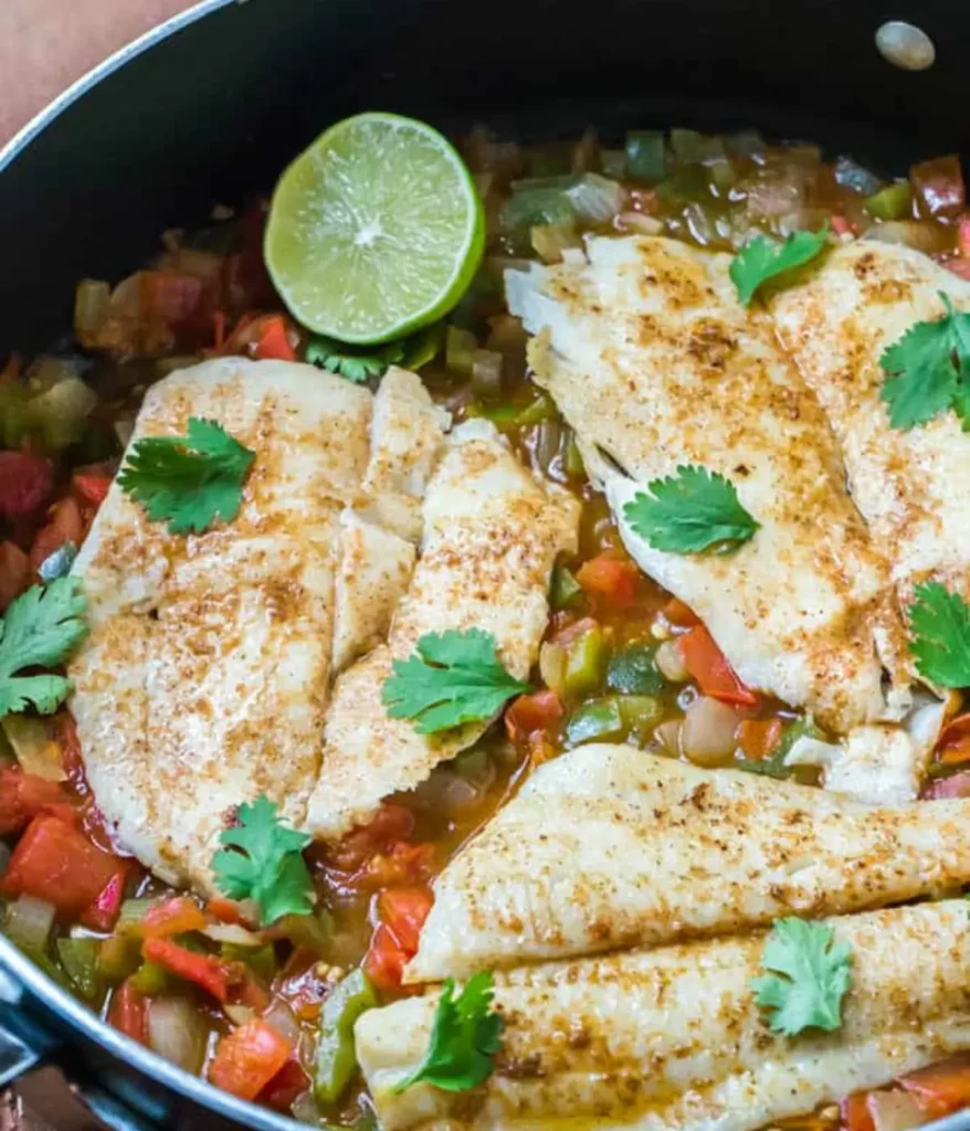 3 spicy creole flounder filet in a pan covered in sauce.