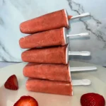 Strawberry mango popsicles with immune boosting nutrients stacked on top of one another on a plate.