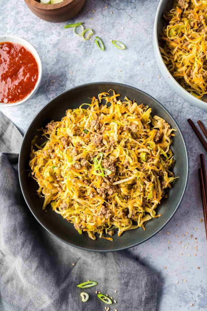 An egg roll in a bowl on a table next to sides.