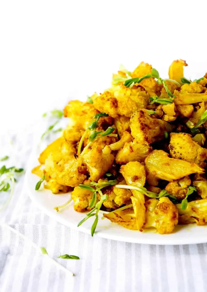 A plate of turmeric roasted cauliflower on a table.