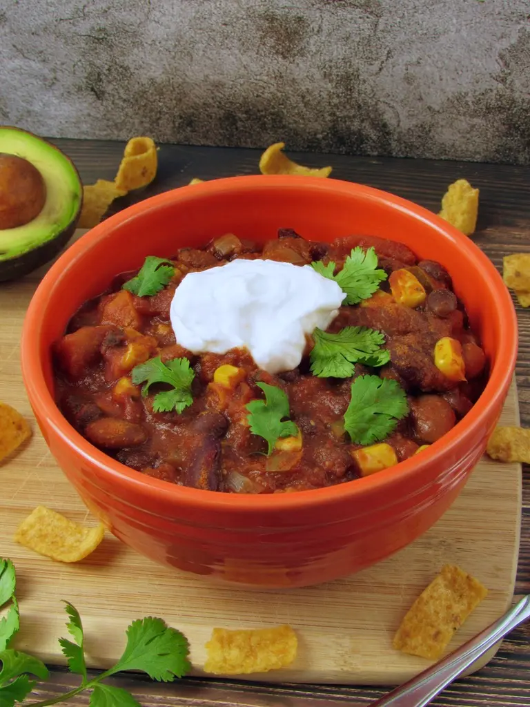 A bowl of instant pot veggie chili topped with sour cream on a table.